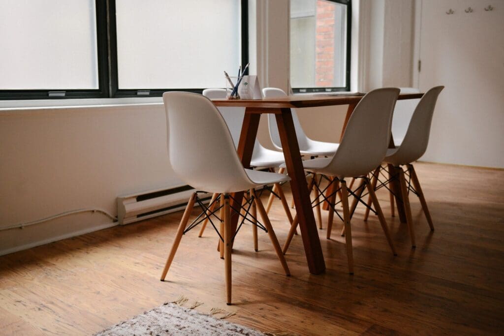 A table with five chairs arranged around it, representing collaboration, guidance, and growth for founders.