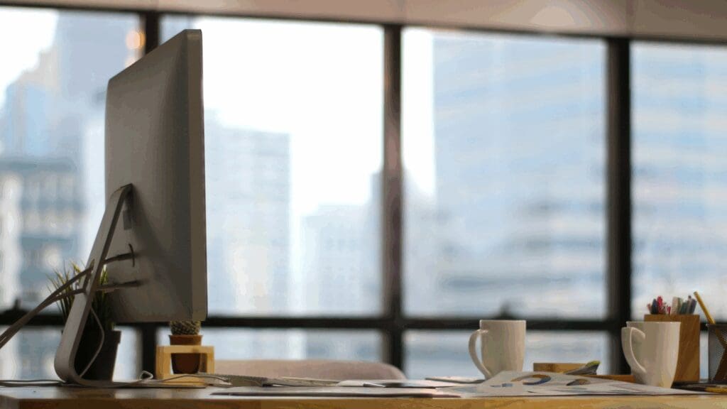Laptop on a desk with two coffee cups in a modern office, symbolizing collaborative leadership coaching and strategic thought partnership.